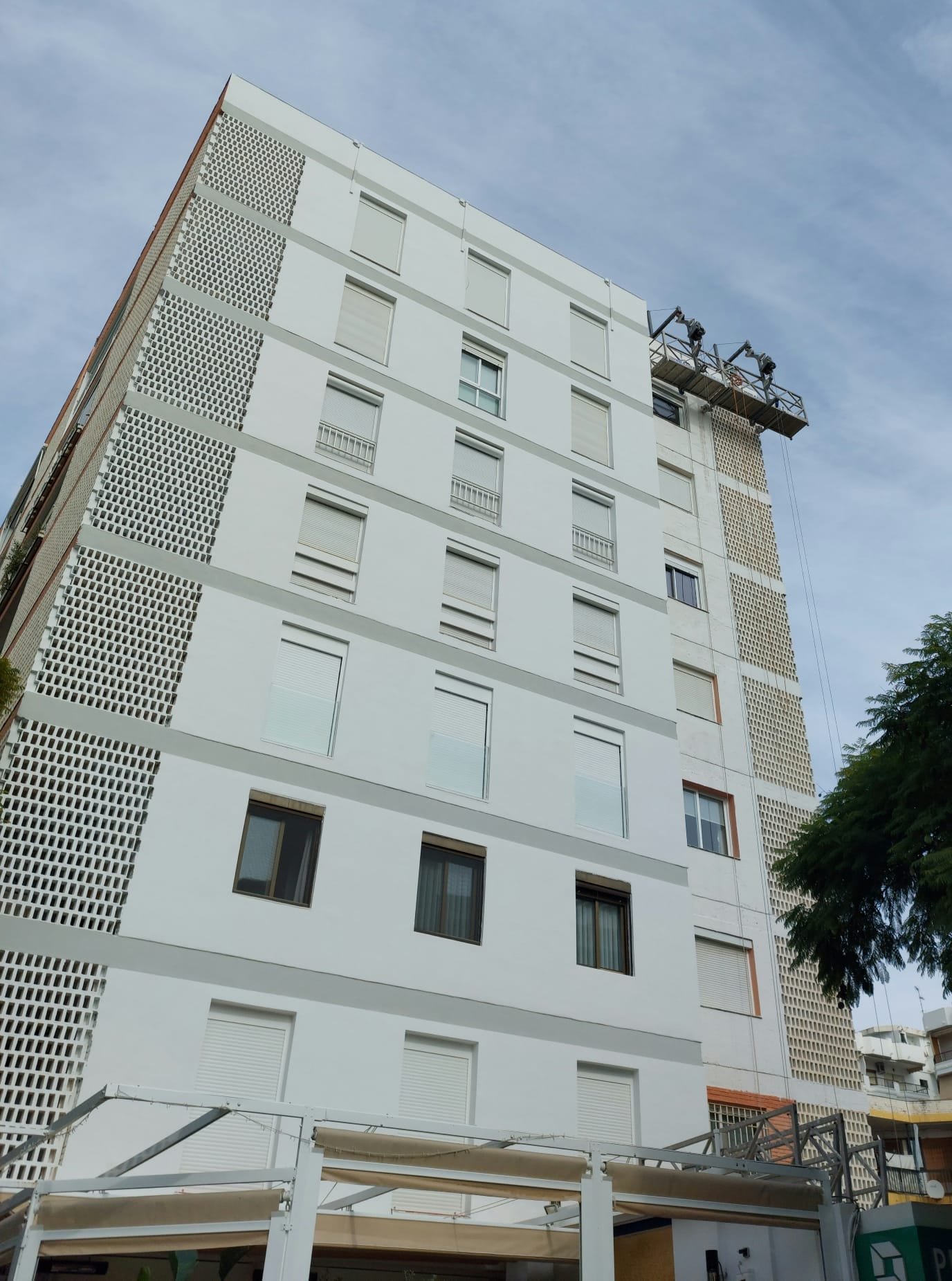 Fachada blanca en proceso con plataforma elevadora