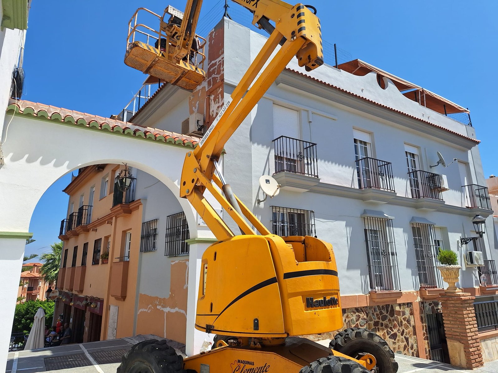 Plataforma elevadora junto a vivienda amarilla